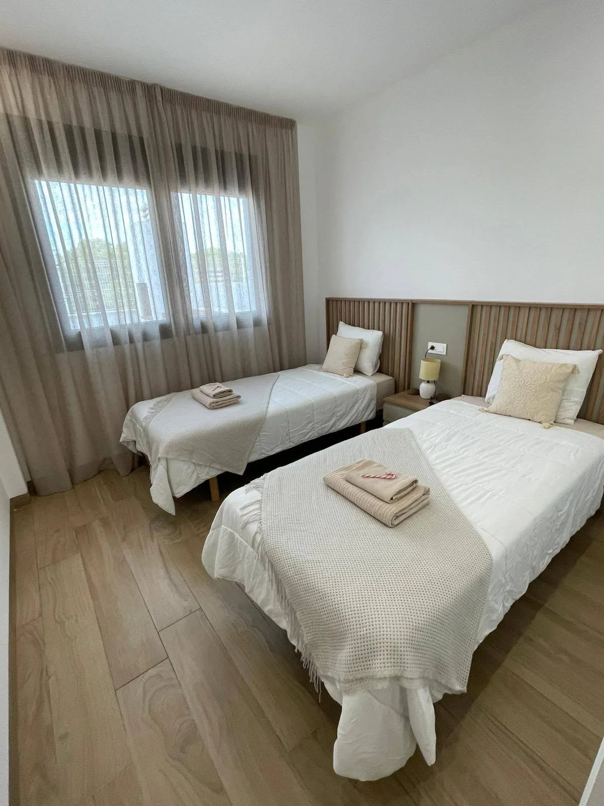 Twee opgemaakte bedden met schone handdoeken, verzorgd door Viana Services